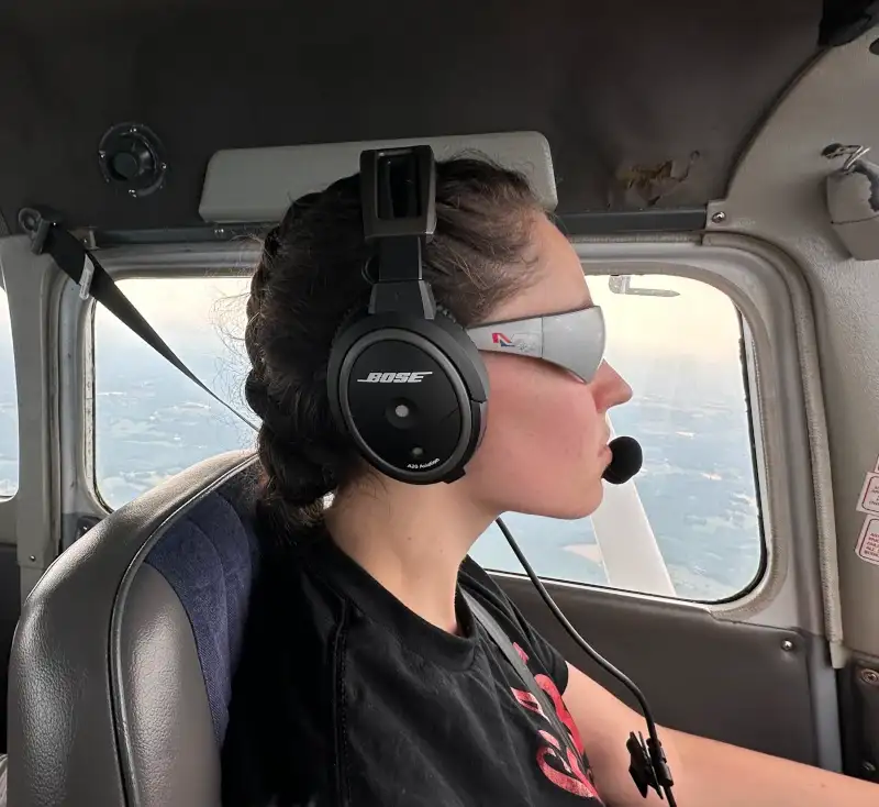 Student pilot wearing a headset and view-limiting glasses during instrument training in the cockpit